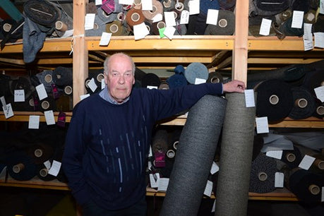 ken kennedy smiling amongst rolls of harris tweed fabric